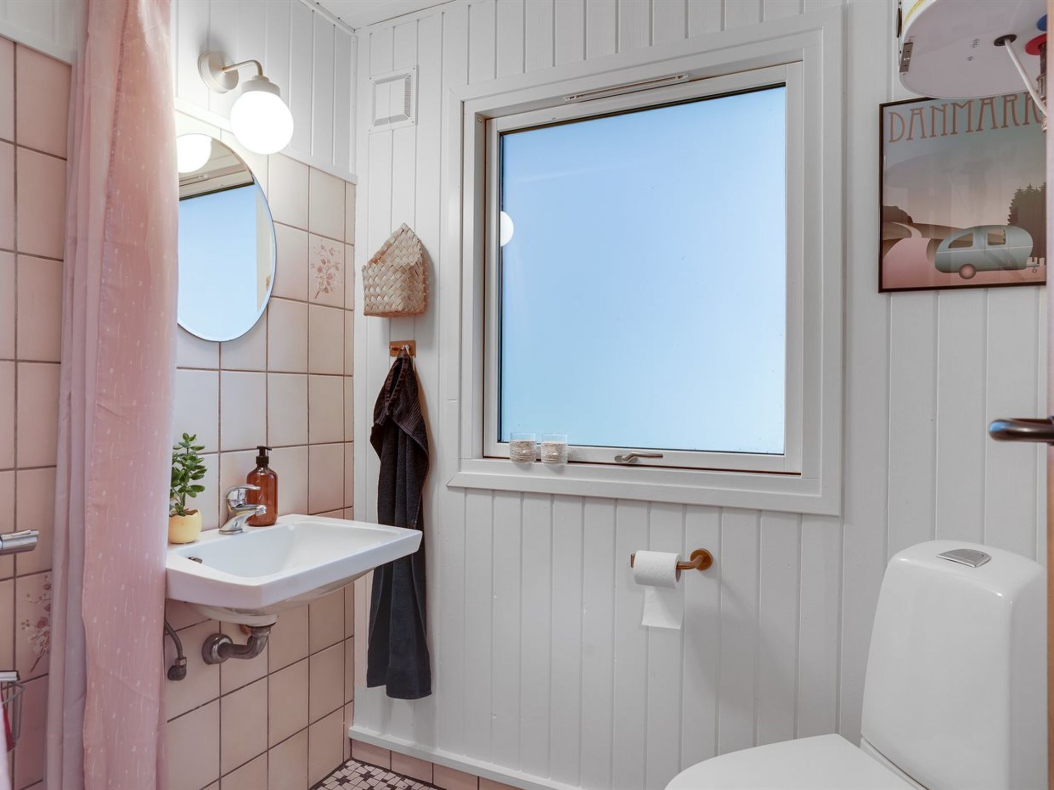 Un bagno con un lavandino bianco, una finestra, un water e una tenda da doccia.