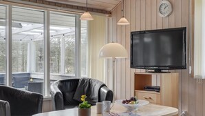 A modern living room with a TV, leather sofa, dining table, and a large window. - "Aneline" - 700m from the sea by Interhome (Saltum)