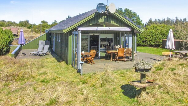 Une petite cabane au toit végétalisé, dotée d’un patio, de meubles d’extérieur et d’une antenne parabolique.