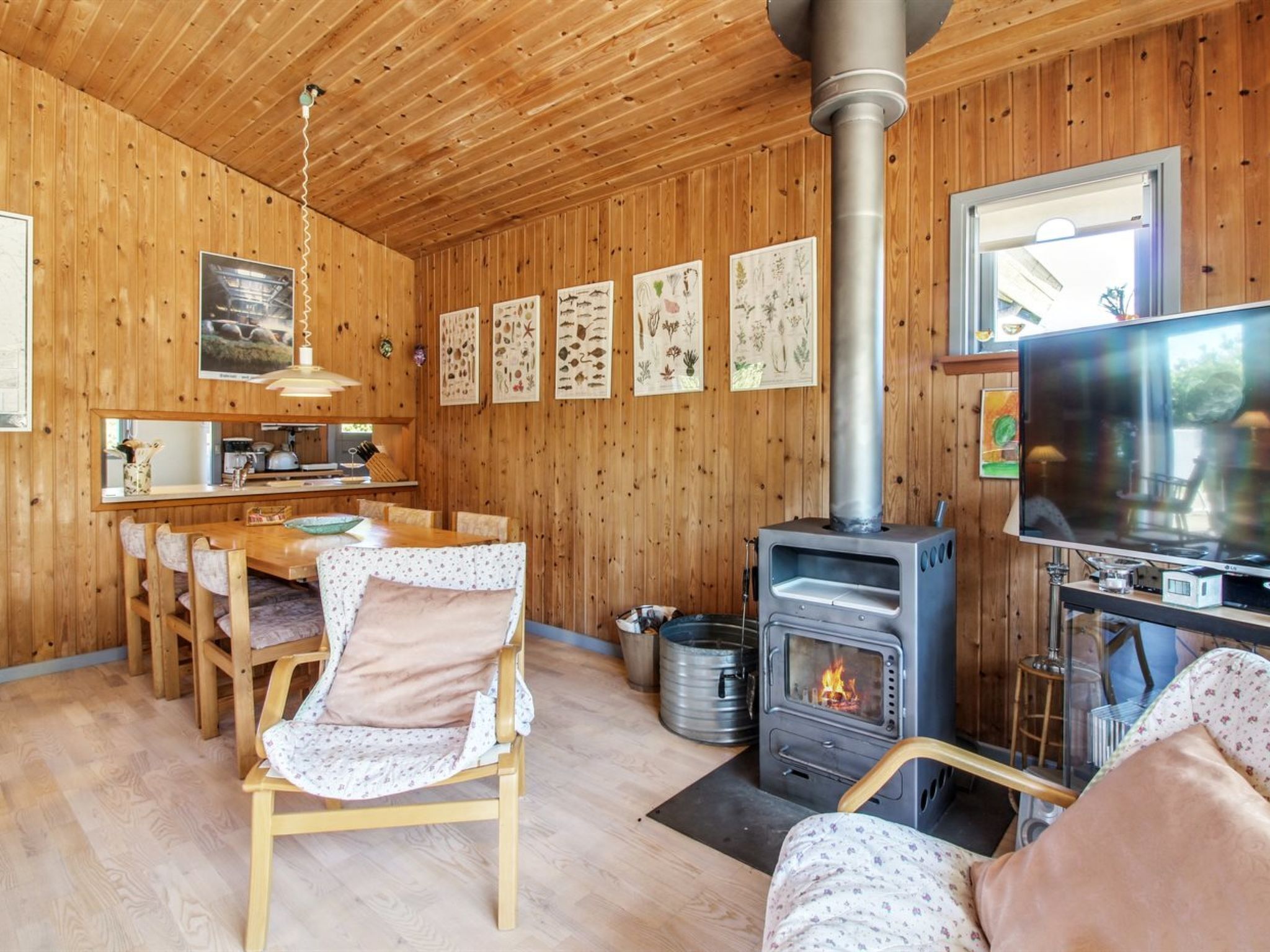 Een gezellig blokhutinterieur met houten accenten, een eethoek, een open haard en een televisie.