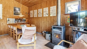 Un intérieur de chalet chaleureux, avec un revêtement en bois, un coin repas, une cheminée et un téléviseur.