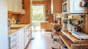 Une cuisine moderne avec des meubles en bois, un évier en acier inoxydable et divers appareils électroménagers, notamment un four à micro-ondes et une machine à café.