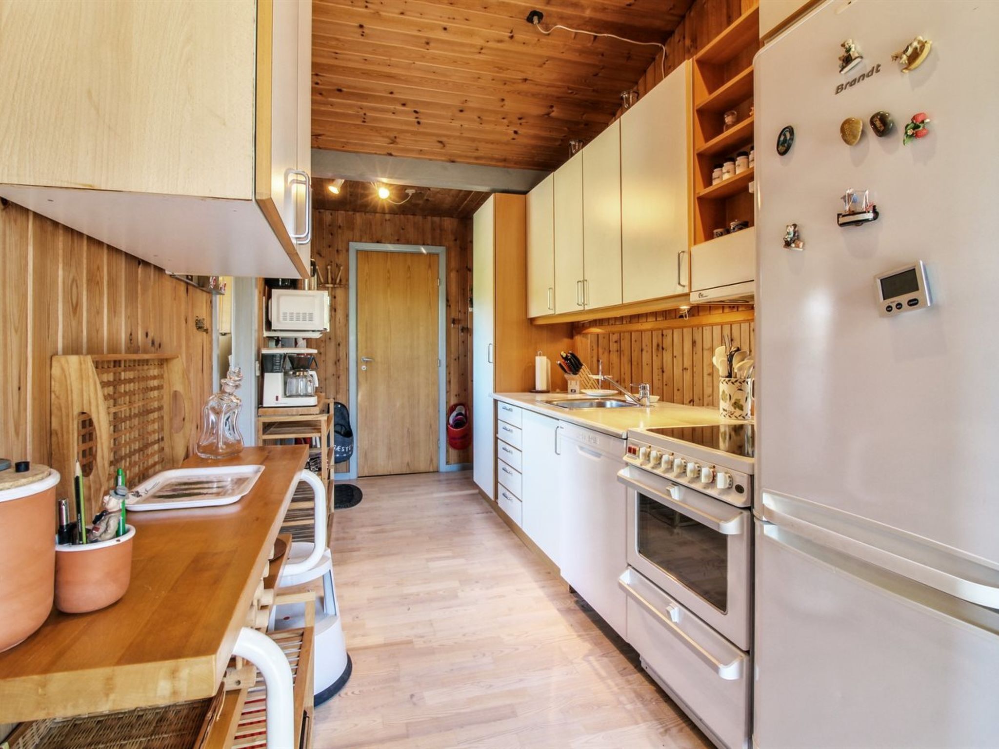 A compact kitchen with wooden cabinets, a built-in microwave, and a stainless steel refrigerator.