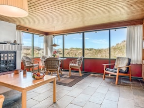 Ein Zimmer mit großem Fenster, Holzboden und einem Tisch mit Stühlen.