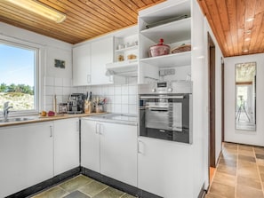Eine moderne Küche mit weißen Schränken, einem eingebauten Backofen und einem Fenster mit Blick auf eine reizvolle Landschaft.