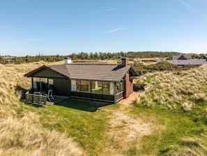 A modern house with a sloped roof, large windows, and a deck.