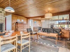 Ein gemütliches Blockhauss-Interieur mit einem Holzespeisetisch, Stühlen, einer Couch und einem Kamin.
