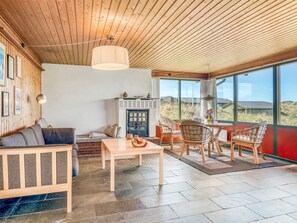 Un intérieur chaleureux avec un plafond en bois, un canapé, une table et des chaises en osier.