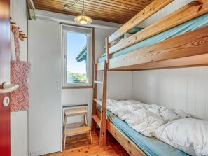 Une chambre avec un lit superposé, un plafond en bois, une fenêtre et une porte.