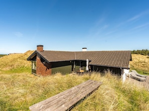 Ein Gebäude mit einem geneigten Dach, einem Schornstein und einer Holzterrasse.