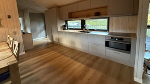 Une cuisine moderne avec des meubles en bois, un four encastré et une fenêtre donnant sur un jardin.