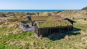 Une zone côtière avec des constructions recouvertes d’herbe, une terrasse en bois avec des sièges et une vue sur la mer.