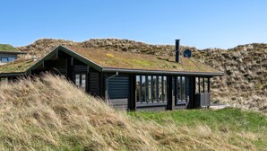 Un bâtiment moderne doté d’un toit végétalisé, de grandes fenêtres et d’un espace extérieur couvert.