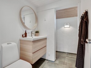 A modern bathroom with a white sink, wooden vanity, a round mirror, and a towel rack. - "Kadife" - 750m from the sea by Interhome (Saltum)