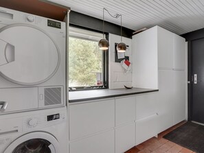 A modern kitchen with a built-in washer and dryer, a window with a view of trees, pendant lights, and white cabinetry. - "Kadife" - 750m from the sea by Interhome (Saltum)