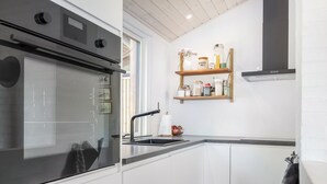 A modern kitchen with a built-in oven, a sink, and wooden shelves above. - "Kadife" - 750m from the sea by Interhome (Saltum)