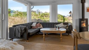Un salón acogedor con un sofá modular, una mesa redonda de madera y un estufa de leña.