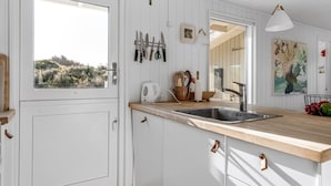 Cocina con muebles blancos, encimera de madera, un lavabo y ventana con vistas al verdor.