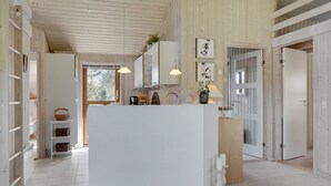 A spacious kitchen with a central island, wooden walls, and a view to the outside.