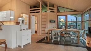 A wooden interior with a dining area, kitchen, and a fireplace.