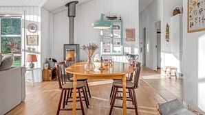 A spacious dining area with a wooden table and chairs, a built-in wood stove, and a light blue pendant lamp. - "Onta" - 900m from the sea by Interhome (Blokhus)