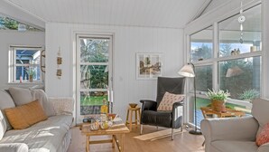 A spacious living room with a large window, a black leather chair, a wooden coffee table, and a grey sofa. - "Onta" - 900m from the sea by Interhome (Blokhus)
