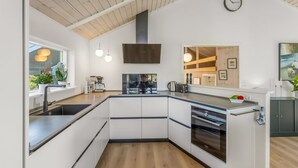 Eine moderne Küche mit Einbauofen, Kaffeemaschine und großem Fenster.