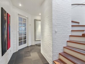 A modern interior with a staircase, white walls, and a door leading to another room.