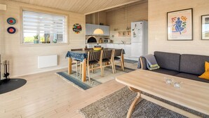 A cozy, well-lit room with a dining area, a sofa, and a kitchen in the background. - "Armgard" - 300m from the sea by Interhome (Løkken)