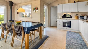 A spacious kitchen with white cabinets, a large dining table, and a wood-burning stove. - "Armgard" - 300m from the sea by Interhome (Løkken)