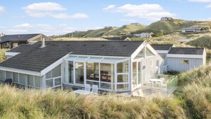 Ein modernes Strandhaus mit großer Glassfront und einer Terrassenfläche.