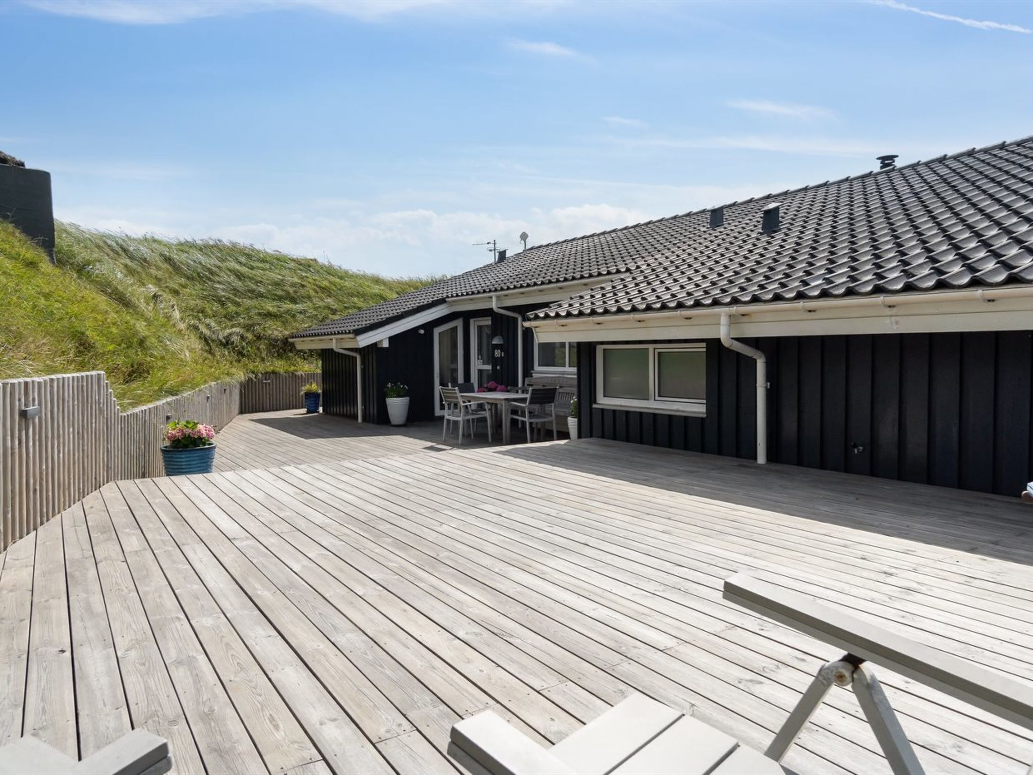 En træterrasse med et spiseområde og et overdækket siddeområde.
