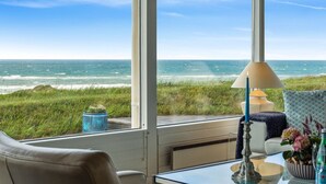 Una habitación con vista al océano, una mesa de vidrio, una lámpara y un sofá.