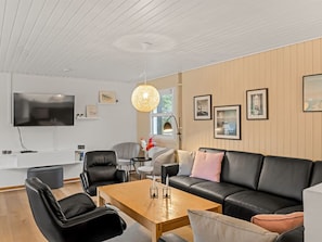 A modern living room with a black leather sofa, a wooden coffee table, and a flat-screen TV mounted on the wall. - "Ingebore" - 700m from the sea by Interhome (Løkken)