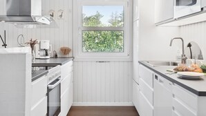 A modern kitchen with white cabinetry, a built-in oven, a microwave, and a window with a view of trees. - "Ingebore" - 700m from the sea by Interhome (Løkken)