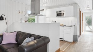 A modern kitchen with white cabinetry, stainless steel appliances, and a central range hood. - "Ingebore" - 700m from the sea by Interhome (Løkken)