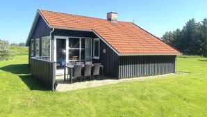 A modern house with a sloped roof and a large glass door leading to an outdoor seating area. - "Frellef" - 491m from the sea by Interhome (Løkken)