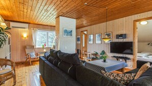 A cozy cabin interior with a wooden ceiling, a sofa, a dining table, and a TV. - "Frellef" - 491m from the sea by Interhome (Løkken)