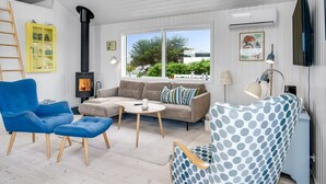Un salon moderne avec un canapé, des fauteuils bleus, une table basse et une cheminée.