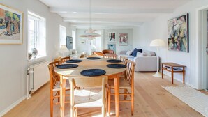 Un comedor amplio con una mesa redonda de madera y sillas, un sofá y una mesita auxiliar.