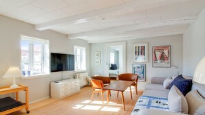 Amplia sala de estar con sofá, mesa de comedor, sillas y televisor.
