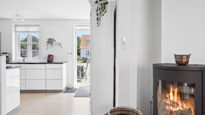 A modern kitchen with white cabinets, a central island, and a stove with a visible fire.