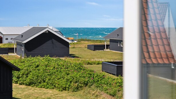 A coastal view with multiple cabins, a grassy area, and a clear sky.