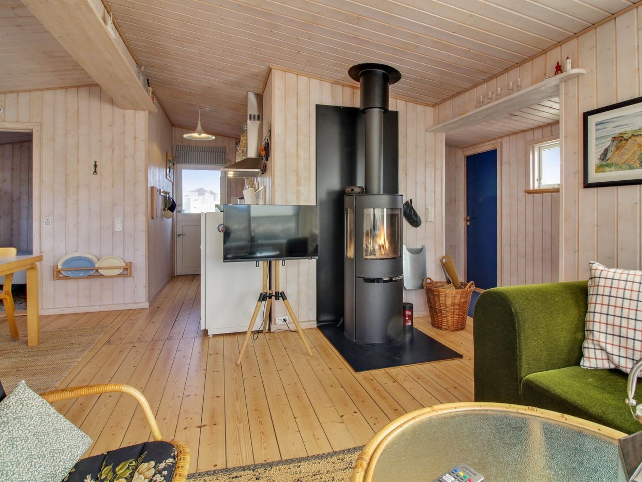 A cozy cabin interior with a wood stove, a dining area, and a living space with a green sofa.