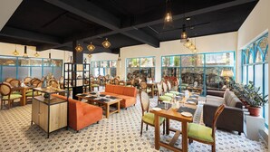 Un restaurante espacioso con techos altos, vigas a la vista y una combinación de asientos de madera y tapizados. Amplias ventanas ofrecen vistas al exterior.