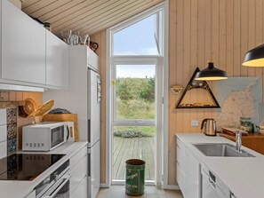 A modern kitchen with white cabinetry, a large window, and a view of the outdoors.