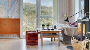 A cozy room with a wooden cabinet, a map, a table with a plant, a sofa with a blanket, and a fireplace.
