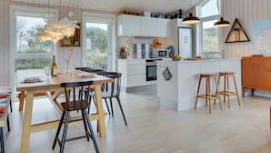 A modern kitchen with white cabinets, a central island with stools, and pendant lighting.