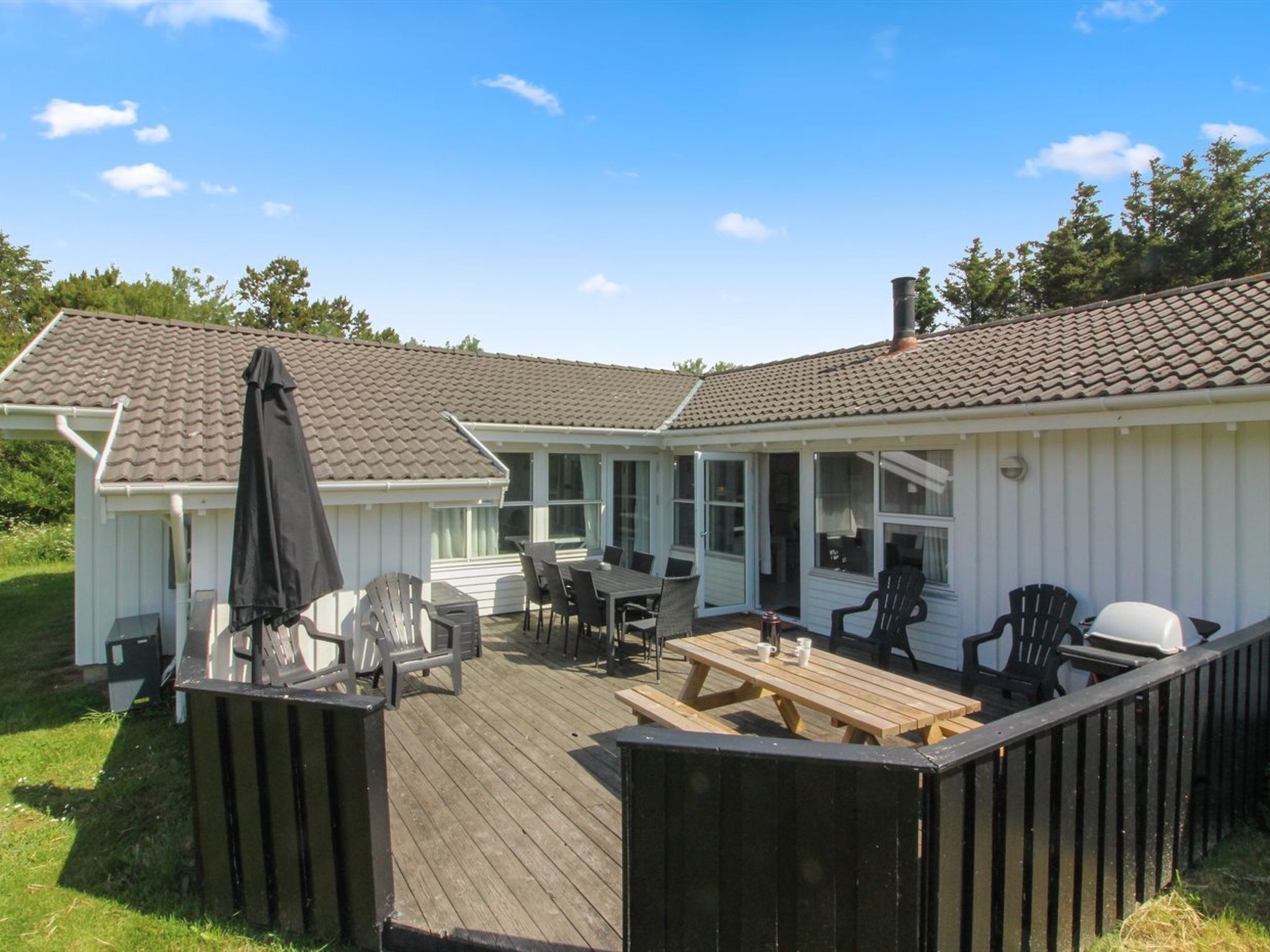 A two-story house with a patio area featuring outdoor furniture and a barbecue grill.