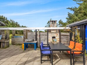 An outdoor patio with a table and chairs, a barbecue grill, and a stone oven.